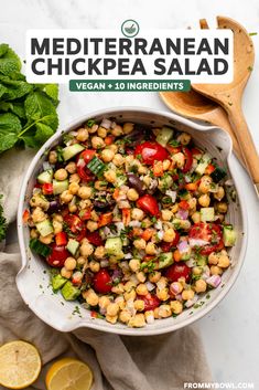 mediterranean chickpea salad in a white bowl with a wooden spoon on the side