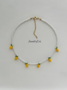 a white beaded necklace with pineapples on it