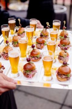 a tray filled with lots of different types of food and glasses full of beer next to each other