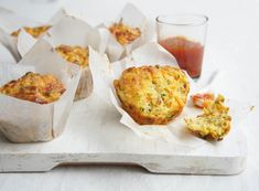 some muffins are sitting on a tray next to a cup of juice and sauce