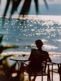 a woman sitting at a table on the beach