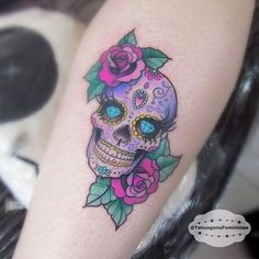 a woman's leg with a tattoo on it that has a skull and roses on it