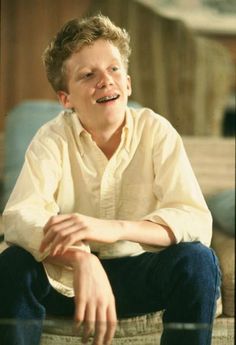 a young man sitting on top of a white chair