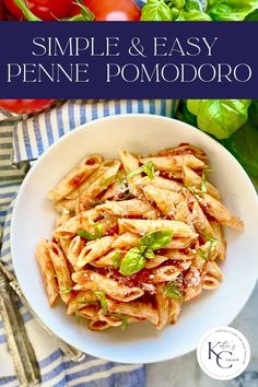 a white bowl filled with penne and sauce next to tomatoes, lettuce and basil