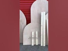 there is a sculpture in front of a red wall that has been painted with white paint