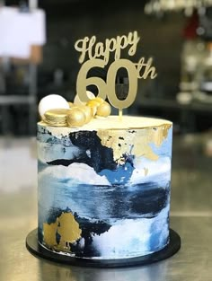 a blue and gold birthday cake with the number sixty on it, sitting on a table