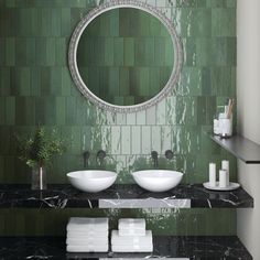 a bathroom with two sinks and a round mirror