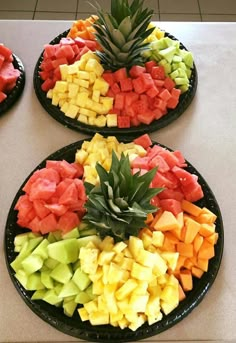 three black plates filled with different types of fruit on top of a white countertop