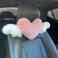 a pink heart with white wings on the back seat of a car