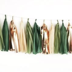 several tassels hanging on a line with gold, green and white ribbons attached to them