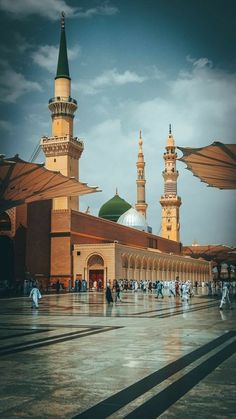 people are walking around in front of an ornate building with green domes and minarets