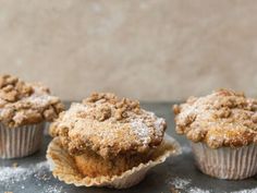 three muffins sitting on top of a table covered in powdered sugar