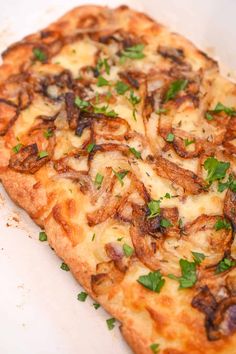 a close up of a pizza on a white plate with parsley sprinkled