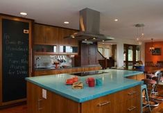 a kitchen with blue counter tops next to a chalkboard on the wall and wooden cabinets