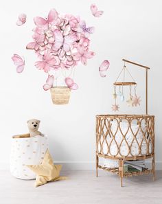 a baby crib with pink flowers hanging from it's ceiling and a teddy bear in the corner