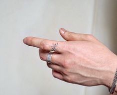 a person's hand with a ring on it and a star tattoo on the middle finger