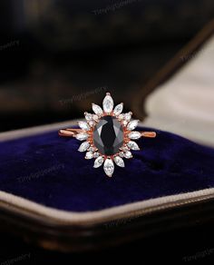 an engagement ring with black and white diamonds on it in a velvet box, close up