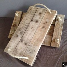 two wooden trays sitting on top of a bed next to each other with rope