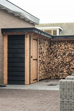 a large pile of wood sitting next to a building on top of a brick sidewalk