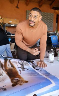 a man sitting at a table in front of a poster