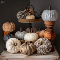 several pumpkins are stacked on top of each other in a display case with wool balls