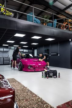 two people working on a pink car in a garage