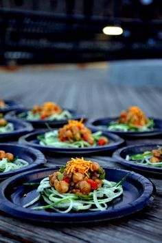 many blue plates with food on them sitting on a wooden table