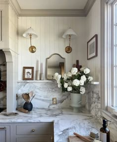 a kitchen with marble counter tops and white flowers in a vase on the counter top