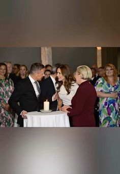 a man and woman standing next to each other in front of a table with a cake on it