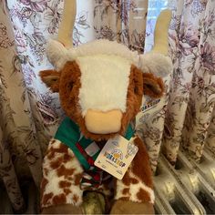 a brown and white cow stuffed animal sitting in front of curtains