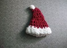 a red and white knitted santa hat laying on top of a gray tablecloth