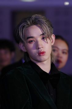 a young man with blonde hair wearing a black suit