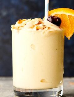 an orange smoothie in a glass with a straw and garnish on top