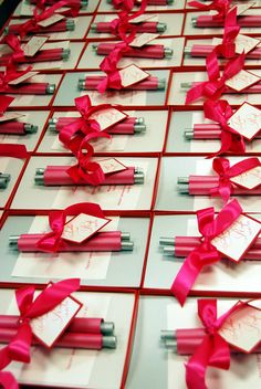 many cards with red ribbons and bows are arranged on the table top, which is covered in white paper