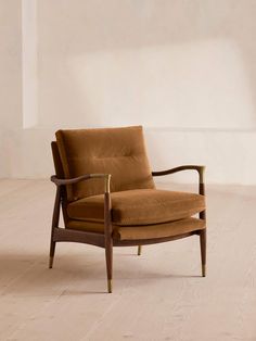 a brown chair sitting on top of a hard wood floor next to a white wall