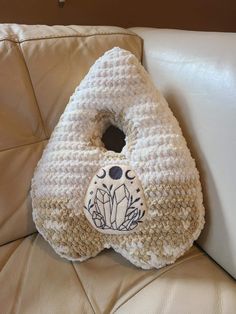 a crocheted bag sitting on top of a white leather couch next to a pillow