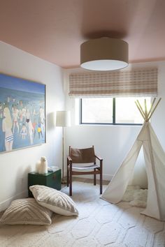 a bedroom with a teepee tent and two pillows on the floor next to a chair