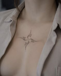 a woman's chest with a small bird tattoo on her left side ribcage