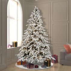 a white christmas tree in a living room with presents on the floor next to it