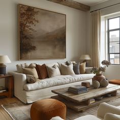 a living room filled with furniture and a large painting on the wall above it's windows