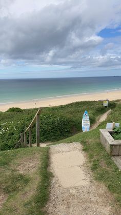 a path leading to the beach with a surfboard on it