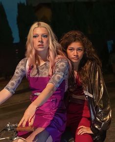 two young women sitting on the back of a motorcycle