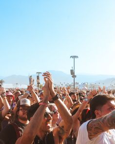 a large group of people standing around each other with their hands up in the air