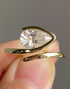 a person holding a ring with a diamond in it's middle and the other hand