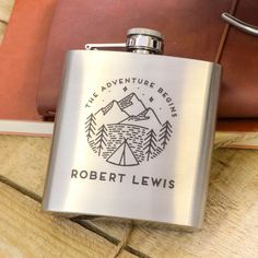 a flask with the words robert lewis on it sitting next to a leather book