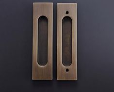 two metal door handles on a black surface