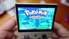 a person holding a nintendo wii game controller in their hand and playing pokemon emerald version on the screen