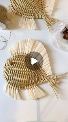 two fish made out of straws sitting on top of a white table next to other items