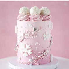 a pink frosted cake decorated with snowflakes and pom - poms