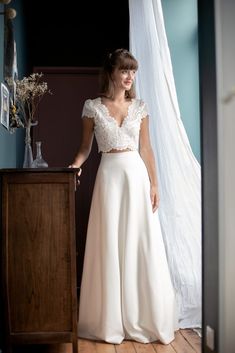 a woman in a white dress standing next to a dresser